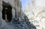 Des Syriens devant les ruines d'un immeuble détruit par un raid aérien le 14 juillet 2016 à Alep