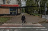 Une femme marche dans une une rue où des filets antidrones ont été disposés,  30 octobre 2026 à Kherson, dans le sud de l'Ukraine 
