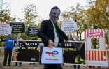 Un militant écologiste porte un masque à l’effigie de Patrick Pouyanné, PDG de TotalEnergies, lors d’une manifestation contre l’austérité gouvernementale et les coupes budgétaires, le 29 octobre 2026 à Paris
