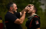 Un pompier insère des gouttes ophtalmiques dans les yeux d'un de ses collègues près de Saint-Magne (sud-ouest) le 11 août 2022  