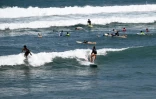 Des touristes surfent sur une plage de Canggu, sur l'île de Bali, le 22 octobre 2024