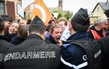 Des gendarmes repoussent des manifestants avant la visite du président Emmanuel Macron, le 19 avril 2023 à Muttersholtz, dans le Bas-Rhin
