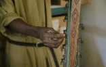 Le frère Lazare ajuste les cordes d'une kora dans l'atelier de fabrication de l'abbaye de Keur Moussa, au Sénégal, le 19 mai 2021