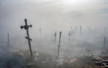 Des croix sous la fumée d'une poubelle dans le cimetière de Mykolaïv, dans le sud de l'Ukraine, le 21 mars 2022
