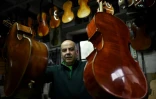 Joaquim Capela porte deux violoncelles, dans l'atelier familial de lutherie, le 15 février 2018