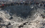Des Palestiniens se rassemblent autour d'un énorme cratère après une frappe israélienne sur un atelier de métallurgie dans le quartier de Zeitoun à Gaza-ville, le 13 avril 2025