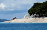 Un engin de chantier drague du sable pour agrandir et consolider une plage artificielle à Primosten, en Croatie, le 9 mai 2025