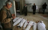 Un Syrien prie près des corps de civils tués par des raids du régime sur le fief rebelle de la Ghouta orientale, avant leur enterrement, le 20 février 2018