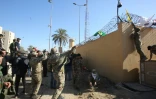 Des membres du Hachd al-Chaabi, coalition de paramilitaires dominée par des factions pro-Iran, accrochent des drapeaux sur les murs d'enceinte de l'ambassade des Etats-Unis à Bagdad lors de protestations le 31 décembre 2019