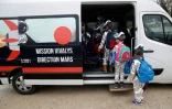 Des élèves de l'Ecole Vivalys en costume spatial montent dans un bus lors du projet ?Mission pour Mars? à Lausanne (Suisse) le 17 mars 2021