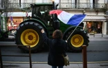 Un agriculteur manifeste avec son tracteur, salué par une passante avec un drapeau français, à Agen, dans le Lot-et-Garonne, le 25 janvier 2024