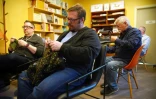 Gene Throwe, au centre, le coordinateur du groupe de tricot pour hommes DC Men Knit, termine de tricoter un pull, entouré d'autres membres du club, à Alexandria, non loin de Washington, le 5 mars 2023