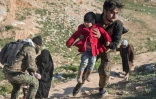 Un combattant des Forces démocratiques syriennes (FDS), soutenues par Washington, aide une femme et ses enfants ayant fui l'ultime poche du groupe jihadiste Etat islamique (EI), le 13 février 2019   