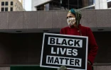 Une femme manifeste le 31 mars 2021 avec un panneau "Black Lives Matter" (les vies noires comptent) devant le tribunal de Minneapolis où se tient le procès du policier blanc accusé du meurtre de George Floyd
