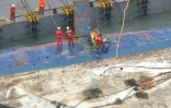 Des ouvriers sur un morceau de la coque du Ferry Sewol lors des opérations de renflouage, le 23 mars 2017 à Jindo