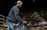 Un ouvrier vénézuélien charge des sacs remplis de carton sur camion dans un entrepôt de Bogota, le 25 mai 2022 