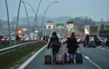 Des voyageurs se rendent à pied à l'aéroport Orly, le 17 décembre 2016 en raison du blocage de l'autoroute par les chauffeurs de VTC