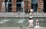 Des habitants et des touristes se rafraîchissent près de la fontaine de la place Kléber à Strasbourg, dans l'est de la France, le 19 juin 2025