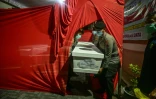 Des policiers transportent le cercueil d'un étudiant, le 5 octobre 2025 à l'hôpital Bhayangkara de Surabaya, tué dans l'effondrement d'un bâtiment de l'internat islamique Al Khoziny à Sidoarjo, en Indonésie