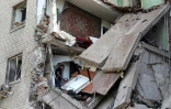 Un homme cherche à récupérer des biens matériels à l'intérieur d'un immeuble endommagé à Bakhmout, dans la région de Donetsk le 28 août 2022