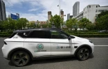 Un robotaxi (g), véhicule autonome sans chauffeur, du projet "Apollo Go" du géant technologique chinois Baidu, dans une rue de Wuhan, le 1er août 2024 dans la province chinoise du Hubei