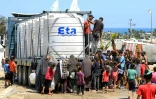 Des Palestiniens dont des enfants se rassemblent autour d'un camion chargé de citernes d'eau pour remplir leurs bidons à Rafah, dans le sud de la bande de Gaza, le 25 juin 2024