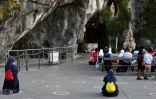 Des pélerins prient devant la Grotte du sanctuaire de Lourdes, le 14 août 2020 dans les Hautes-Pyrénées