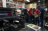 Le maître imprimeur Olmedo Franco (g) et des collaborateurs vérifient une affiche imprimée à La Linterna, le 2 mars 2021 à Cali, en Colombie