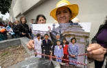 Une partisane de l'ex-président péruvien Alberto Fujimori montre une photo d'Alberto Fujimori et de sa famille alors qu'elle attend d'entrer au ministère de la Culture pendant les funérailles nationales à Lima, le 13 septembre 2024