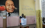 Un représentant de la commission électorale compte les votes de la présidentielle ivoirienne devant un tableau du premier président de Côte d'Ivoire, Félix Houphouët-Boigny, le 25 octobre 2025 à Abidjan