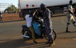 Un policier fouille un vendeur à moto à Cinkassé, un poste frontalier commercial du nord du Togo avec le Burkina Faso, le 16 février 2020
