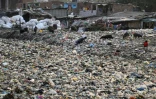 Un chiffonier dans un canal d'évacuation des égoûts rempli de déchets plastiques dans le bidonville Taimur Nagar à New Delhi le 30 mai 2018