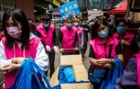 Des partisans de Pékin distribuent des masques dans un marché à Hong Kong le 15 mars 2020