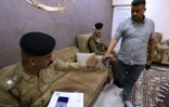 Un officier de police irakien enregistre l'arme d'un citoyen Ă son domicile dans un quartier de Bagdad, le 13 mai 2024