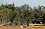 Une photo prise à partir du  Golan occupé par Israël, montre des membres des forces syriennes arborant un drapeau national de l'autre côté de la ligne de démarcation, le 26 juillet 2018
