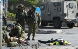 Des soldats israéliens portent secours à un des leurs (g) alors que le corps du palestinien auteur du coup de couteau gît au sol (d) à l'entrée d'Hébron en Cisjordanie occupée, le 16 octobre 2015