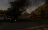 Un blindé de l'armée ukrainienne près d'un véhicule en feu, à proximité de la frontière avec la Russie, dans la région de Soumy le 14 août 2024