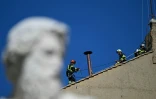 Des pompiers installent une cheminée sur le toit de la Chapelle Sixtine, au Vatican, quelques jours avant le début du conclave, le 2 mai 2025