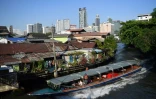 Une navette fluviale longe un quartier pauvre de Bangkok, tout près de buildings modernes, le 13 mars 2019