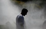 Un homme marche sous un système de brumisation installé lors d'une vague de chaleur à Strasbourg, dans l'est de la France, le 20 juin 2026