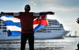 Un homme brandit le drapeau cubain à l'arrivée du premier navire de croisière américain en un demi-siècle au port de La Havane, le 2 mai  2016
