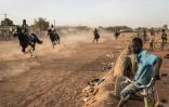 Un jeune garçon assis sur son vélo regarde une course de chevaux, à Ouagadougou le 30 janvier 2022