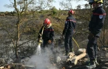 Des pompiers éteignent des cendres chaudes à côté d'Albas, dans le massif des Corbières, le 9 août 2025
