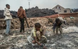Des enfants ramassent de la lave près de Goma, le 23 mai 2021 après l'éruption du volcan Nyiragongo, en RDC