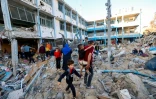 Des Palestiniens au milieu des destructions après une frappe sur une école abritant des déplacés palestiniens à Bureij, dans le centre de la bande de Gaza, le 7 mai 2025