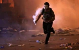 Un manifestant masqué court avec une grenade lacrymogène lors de heurts avec les forces de sécurité, le 18 octobre 2019 à Beyrouth, au Liban