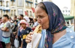 Une femme mange un sandwich préparé par le vendeur de street food Habib el-Bey le 2 juillet 2022 sur l'avenue Habib Bourguiba, à Tunis