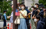 Des badauds regardent le passage des cortèges officiels près de la résidence du Premier ministre japonais à Tokyo le 24 mai 2022, pendant le sommet des dirigeants du Quad