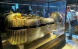 Des touristes admirent le sarcophage extérieur en bois doré de l'ancien roi égyptien Toutânkhamon au musée du Caire, le 11 juin 2025