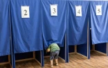 Un enfant jette un oeil dans un isoloir lors des élections européennes, le 9 juin 2024 à Chisinau, en Moldavie 